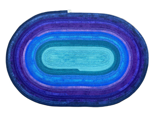Oval-shaped rug with blue and purple gradient on a wooden floor